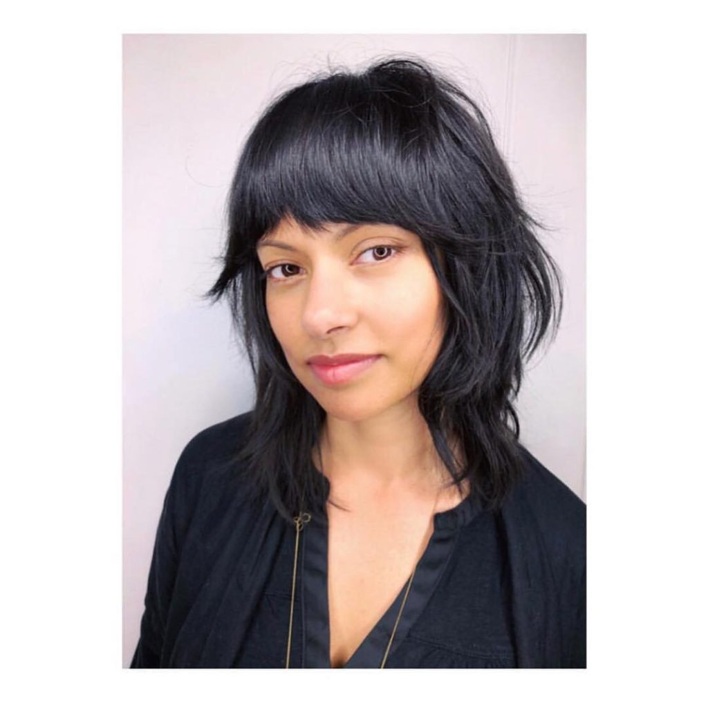 Black Shaggy Razor Cut Bob with Full Fringe Bangs and Undone Texture Medium Length Hairstyle