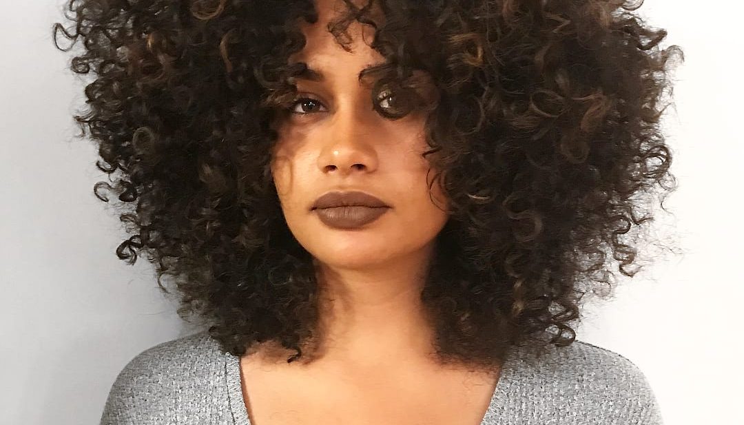 Highlighted Brunette Fro with Voluminous Spiral Curls and Disconnected Center Part Medium Length Hairstyle