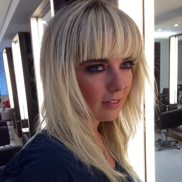 Long Shaggy Hair with V-Cut Layers and Full Blunt Bangs on Blonde Hair with Dark Roots