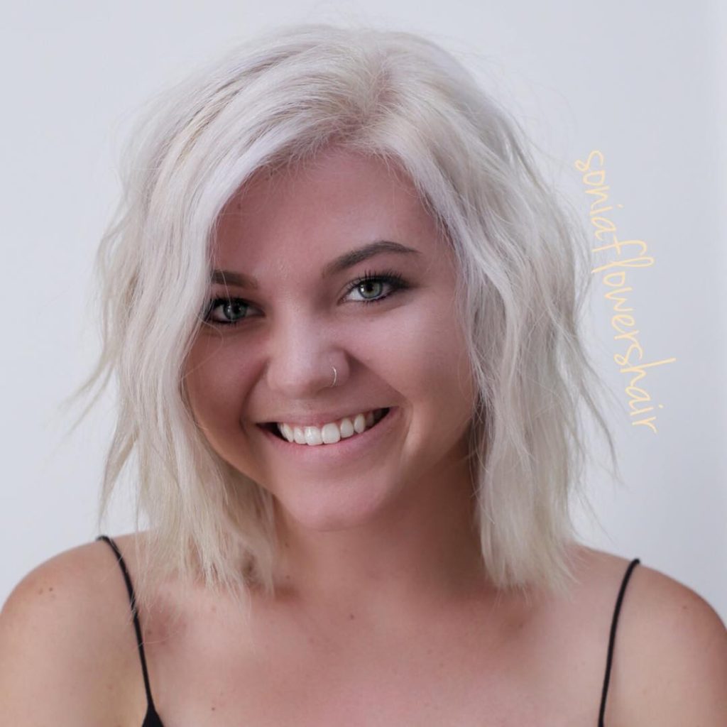 Platinum Blonde Layered Bob with Wavy Texture and Long Side Swept Bangs Medium Length Trendy Hairstyle