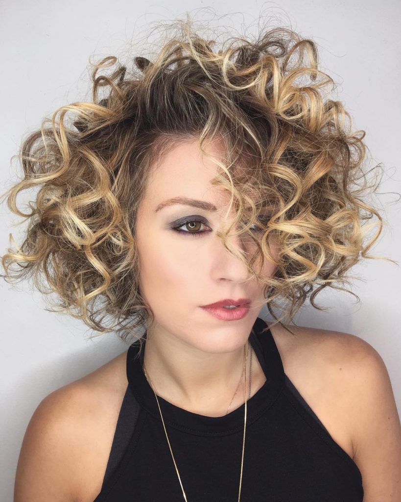 Shaped Bob with Large Messy Spiral Curls and Blonde Balayage Hair Color Medium Length Fall Hairstyle