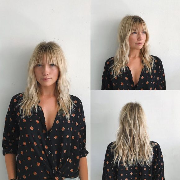 Wavy Blonde Layered Cut with Brow Skimming Bangs and Highlights